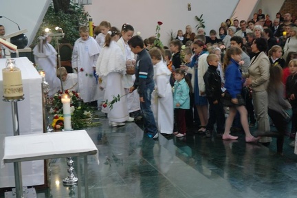 Dzieci składają kwiaty przed obrazem Matki Bożej